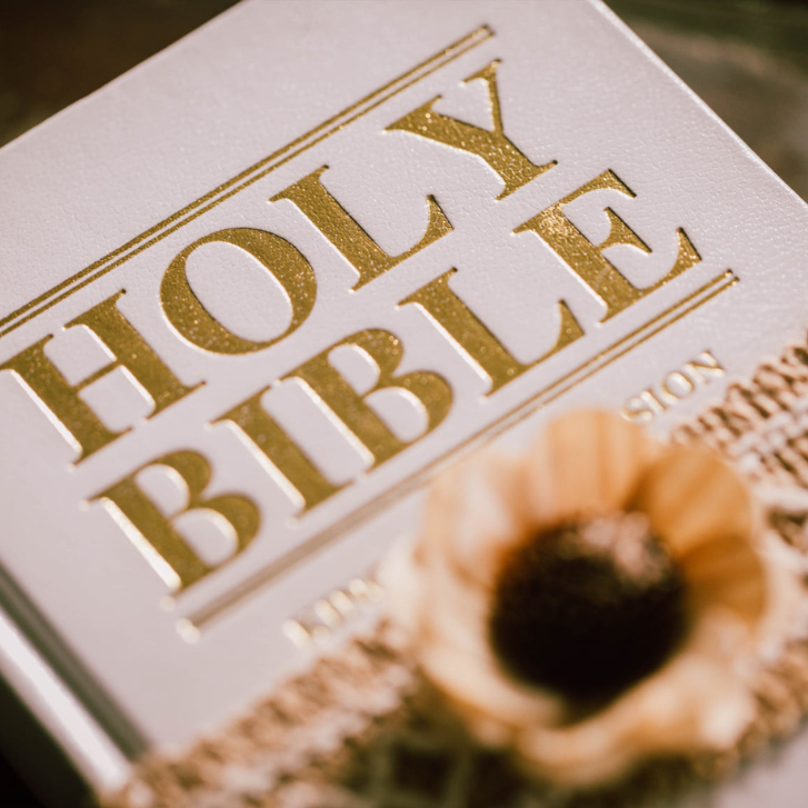Weißes Buch mit goldener Schrift "HOLY BIBLE" und einer dekorativen Blume.