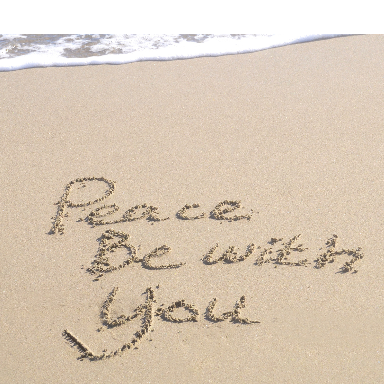 Auf sandigem Strand steht „Peace Be with you“ in sanften Buchstaben.